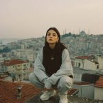 Person in gray tracksuit on urban rooftop.