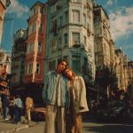 Couple standing in front of old colorful buildings.
