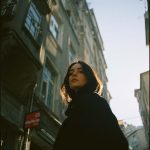 Person standing near old buildings in sunlight