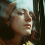 Person in hat looking through window.