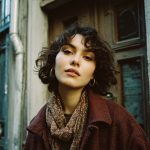 Person with curly hair wearing patterned scarf outdoors.