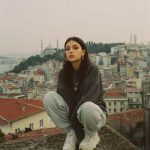 Person sitting on rooftop with cityscape background