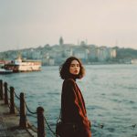 Woman by waterfront with cityscape background