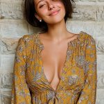 Smiling person in floral dress against stone wall.
