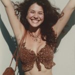 Smiling woman with arms raised, sunny day