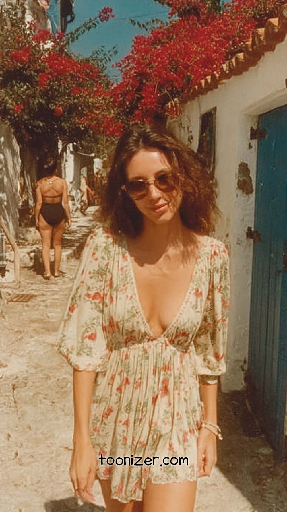 Woman in floral dress on sunny street.