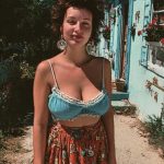 Person standing outside colorful house on sunny day.