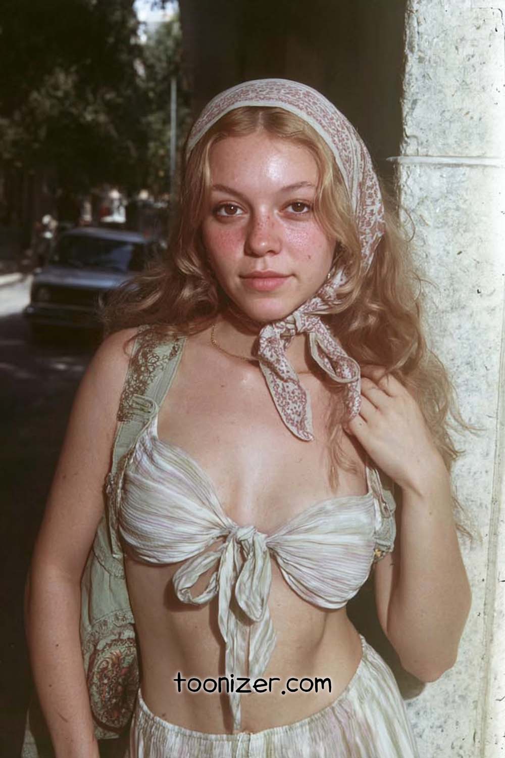 Young woman in headscarf and tie-front top outdoors.