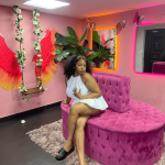 Woman in white dress on pink sofa in colorful room.