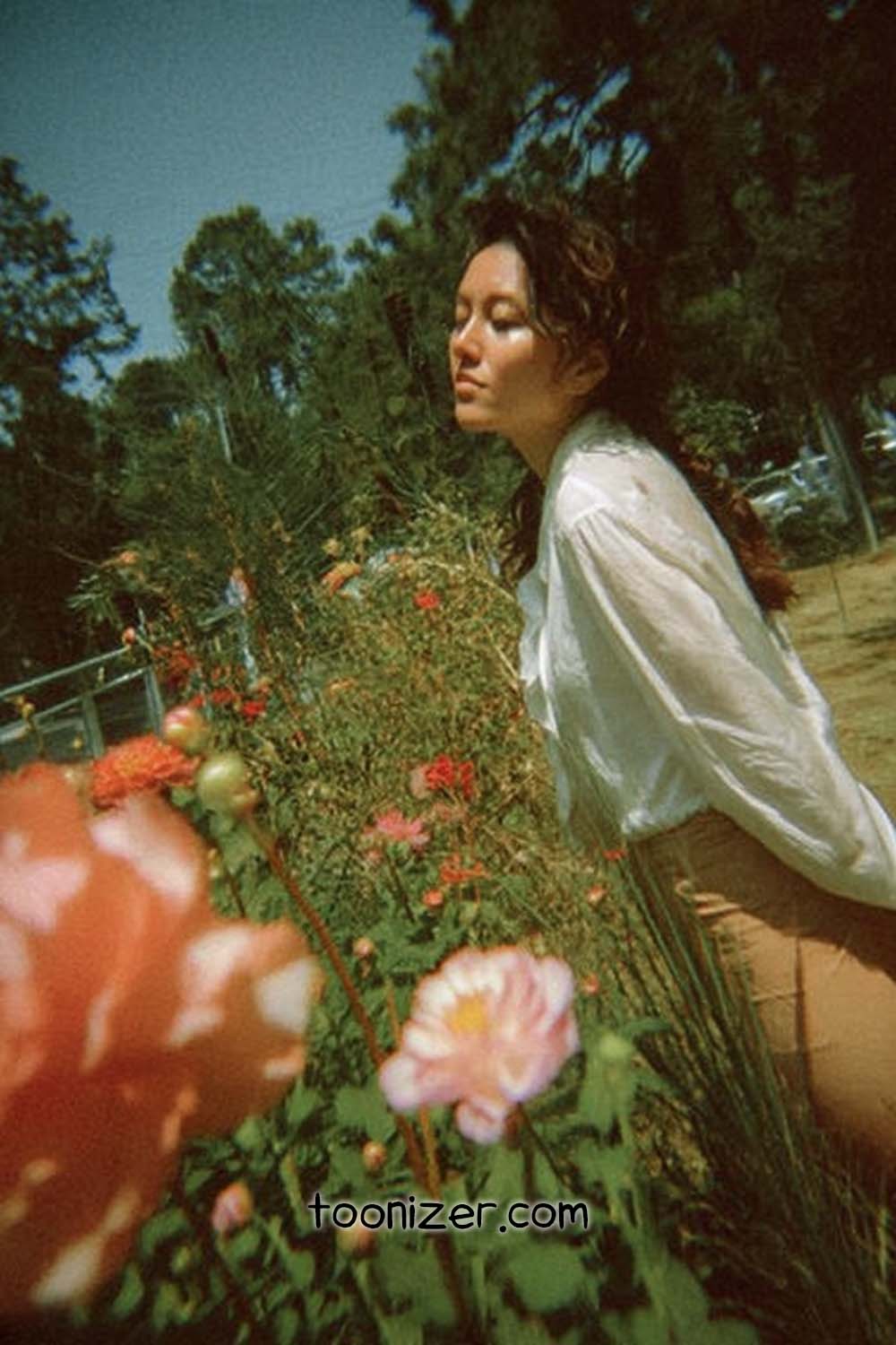 Woman in field with flowers, serene atmosphere.