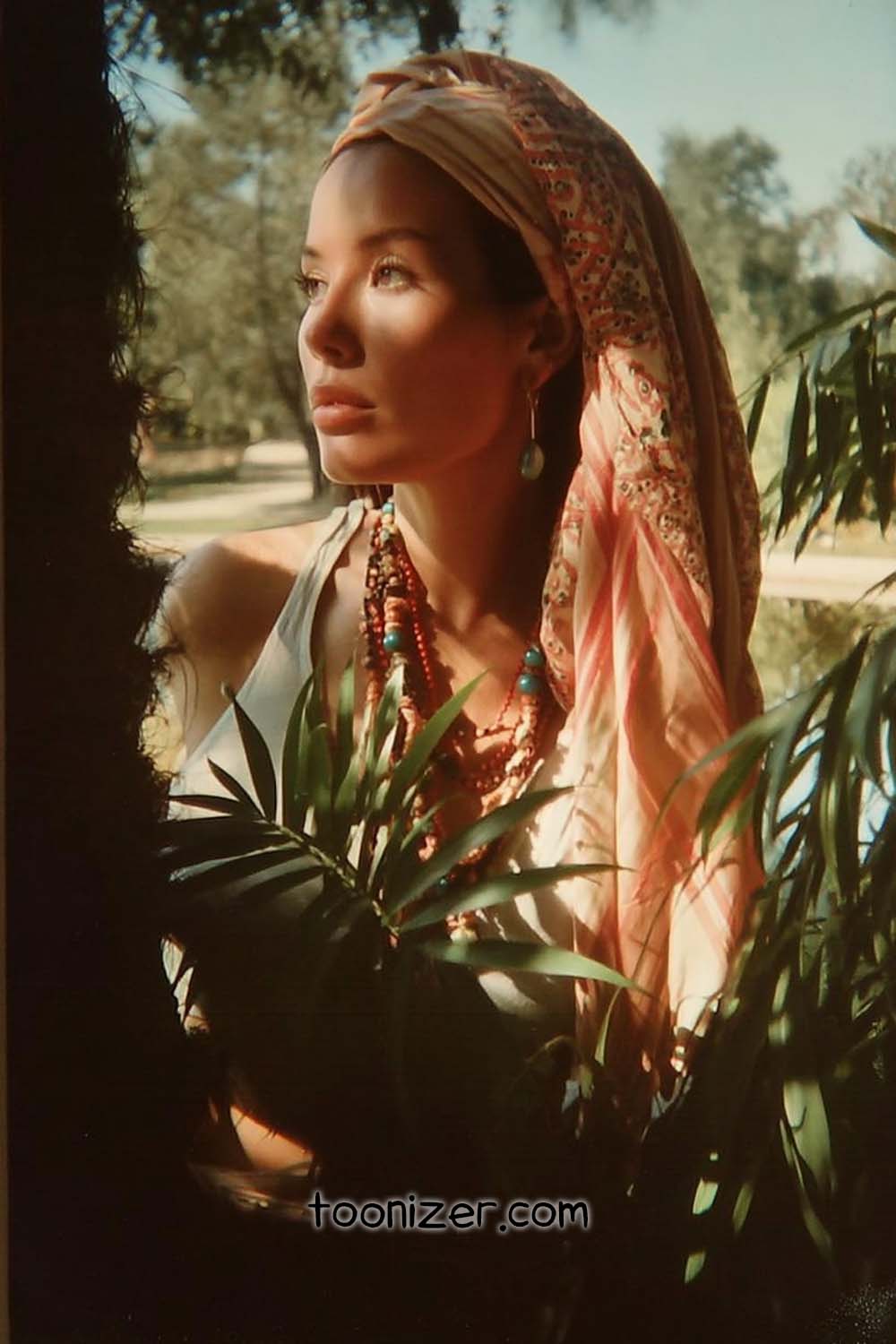 Woman with headscarf and jewelry in sunlight.