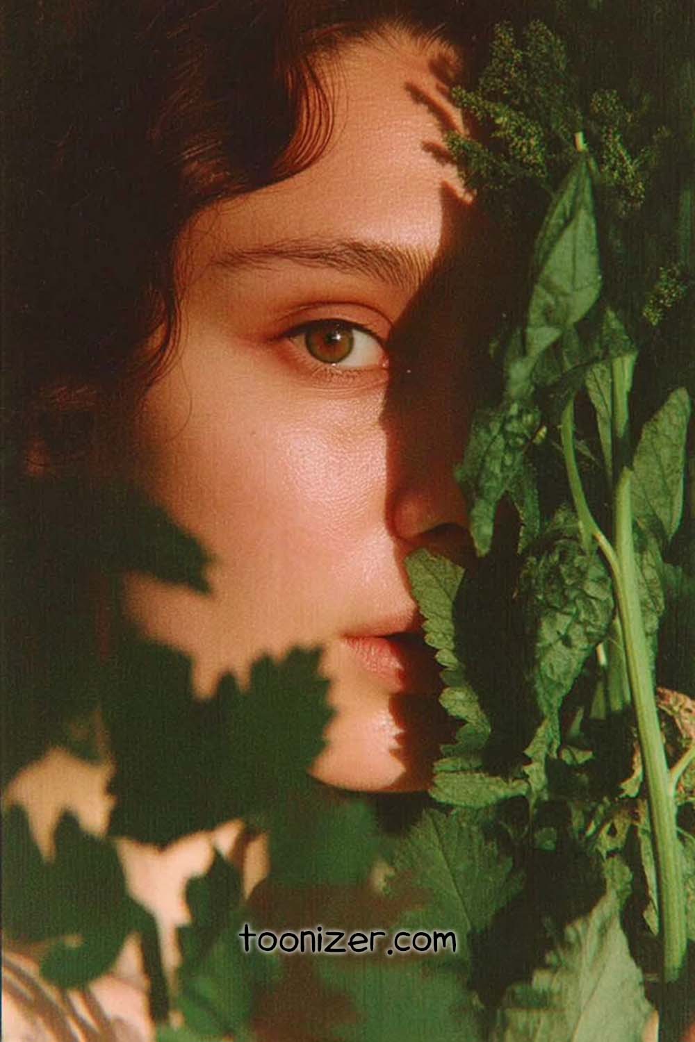 Person partially hidden behind green leaves.