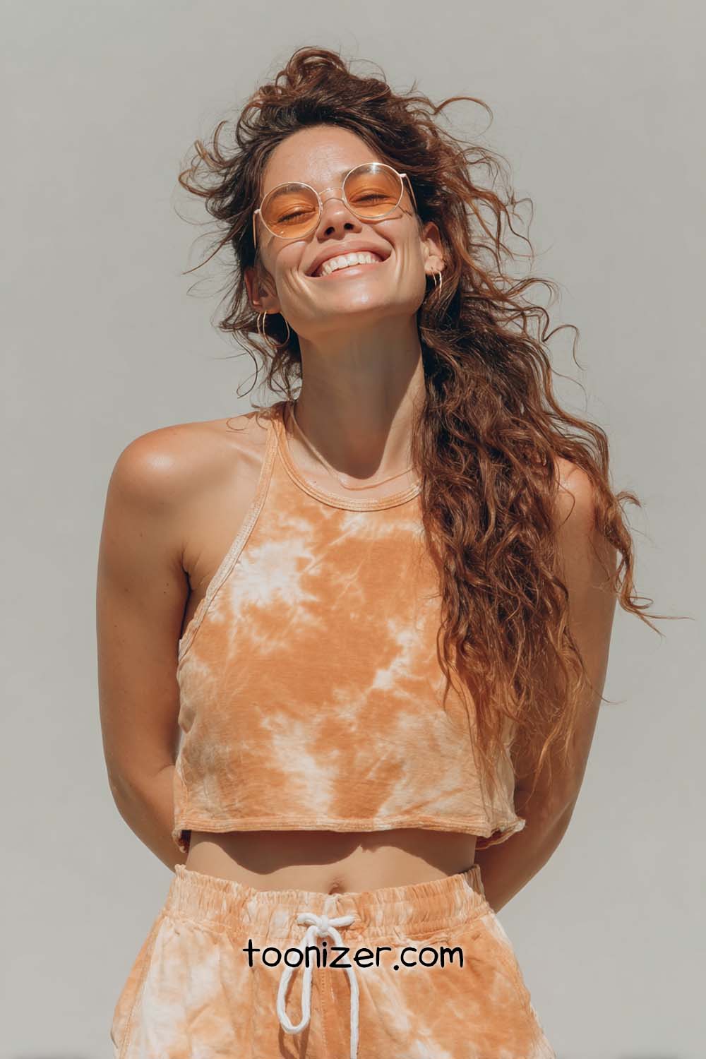 Smiling woman in orange tie-dye outfit outdoors.