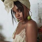 Woman in lace headscarf with apple earrings.