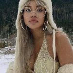 Woman in winter hat and glasses in snowy background.