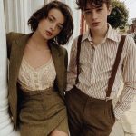 Two people in vintage outfits outside building.