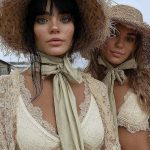 Two people in lace clothing and straw hats.