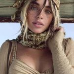 Woman in floral headscarf and tan outfit