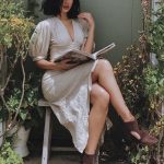 Woman reading book outdoors in garden chair.