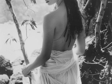 Woman in flowing dress by rocky shoreline