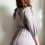 Woman in patterned dress posing sideways.