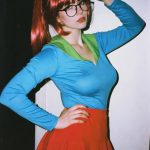 Woman in Velma-inspired cosplay posing indoors