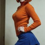Woman with red bob in orange sweater and skirt