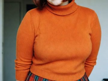 Woman in orange sweater and plaid skirt indoors