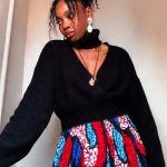 Woman in black sweater and colorful skirt.