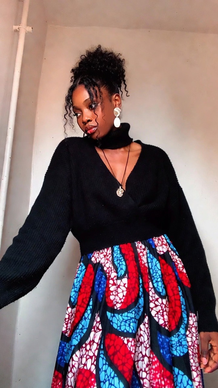 Woman in black sweater and colorful skirt.