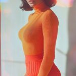 Woman in orange outfit with red glasses