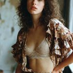 Woman in floral outfit and lace bralette indoors