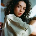 Curly-haired woman sitting by window in soft light