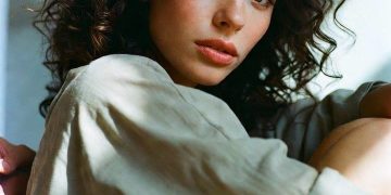 Curly-haired woman sitting by window in soft light