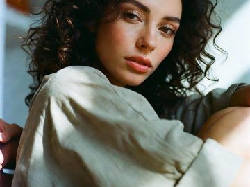 Curly-haired woman sitting by window in soft light