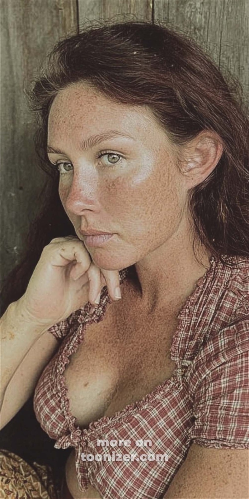 Freckled woman in plaid blouse resting her chin