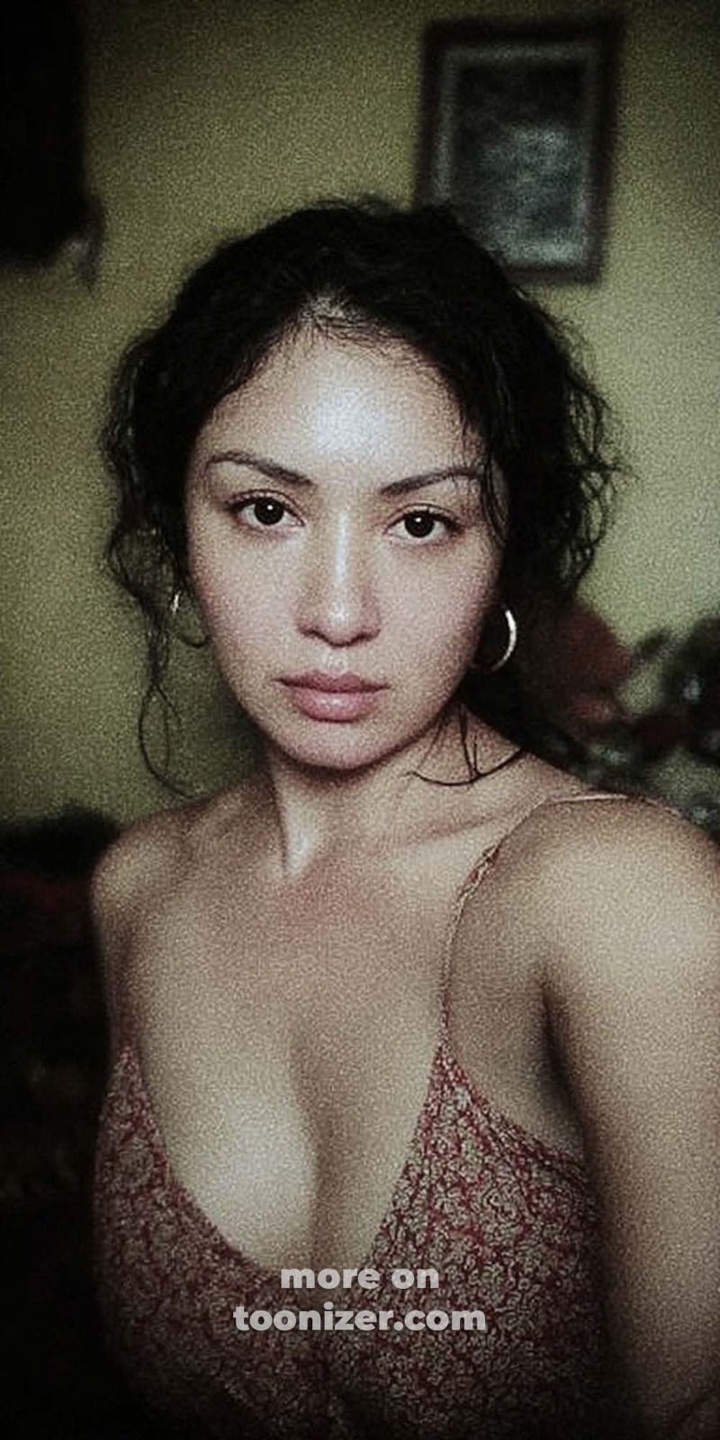 Woman in patterned camisole looking at camera indoors