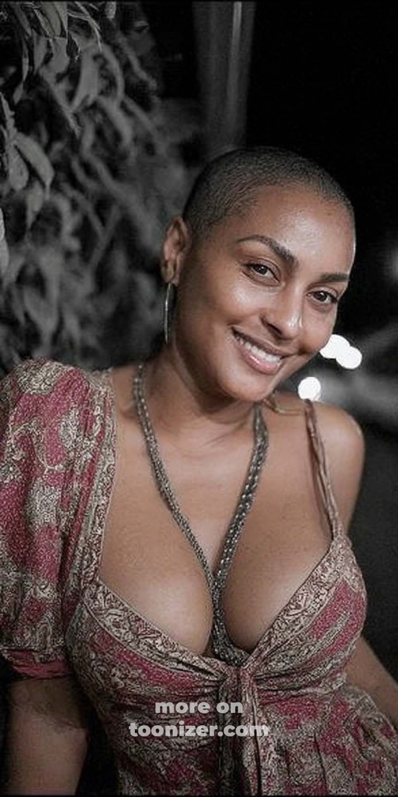 Smiling woman with shaved head in patterned dress