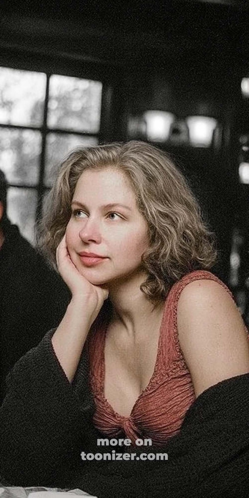 Woman with short wavy hair resting on hand indoors