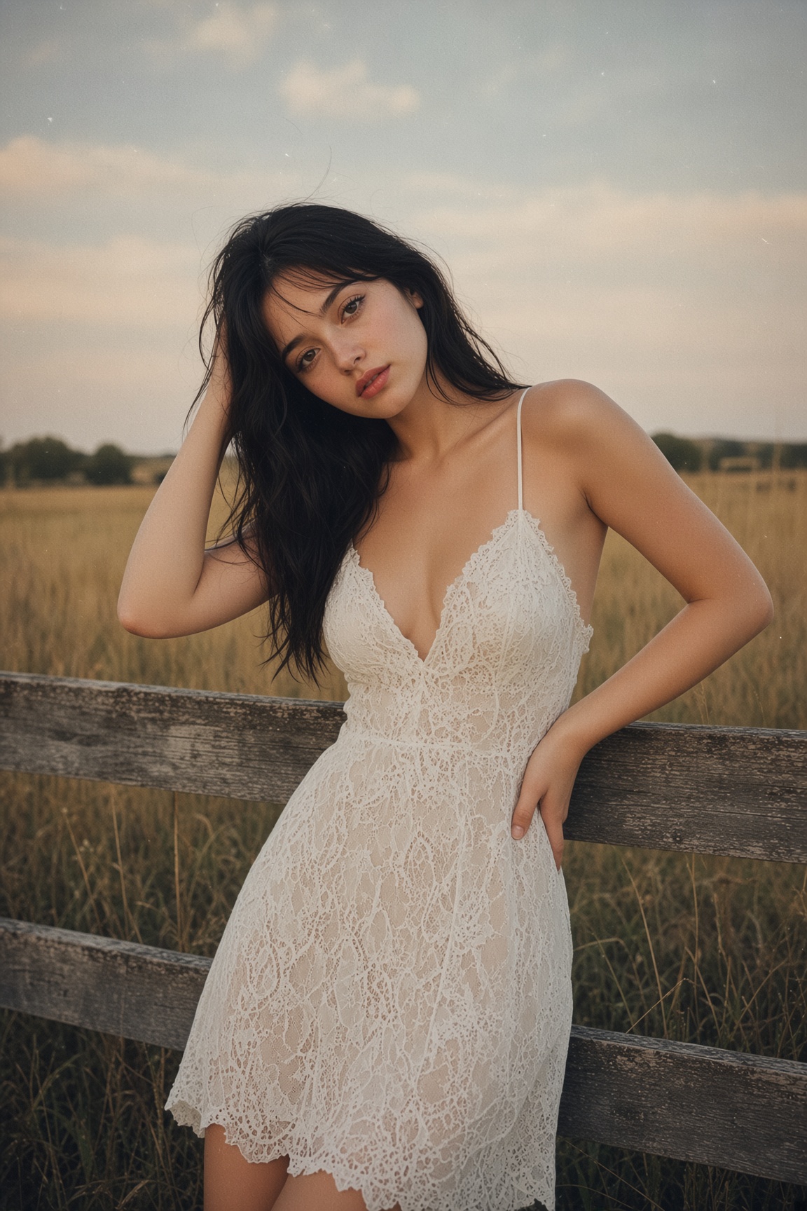 Woman in white lace dress beside rustic fence